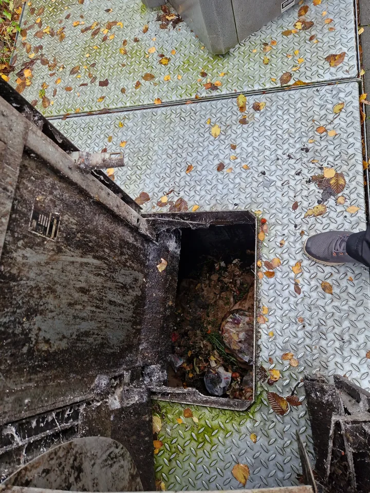 Blick von oben in einen geöffneten, stark verschmutzten Unterflurbehälter